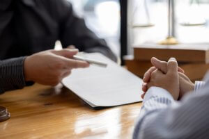 Client and lawyer reviewing paperwork at a wooden table, representing clear legal consultation in progress.